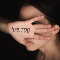 Girl covers her face with hand with hashtag metoo against sexual harassment